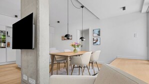 Een moderne eetruimte met een houten tafel, witte stoelen en hanglampen.