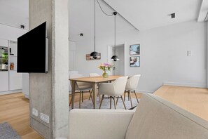 Ein moderner Essbereich mit Holztisch, weißen Stühlen und Pendelleuchten.