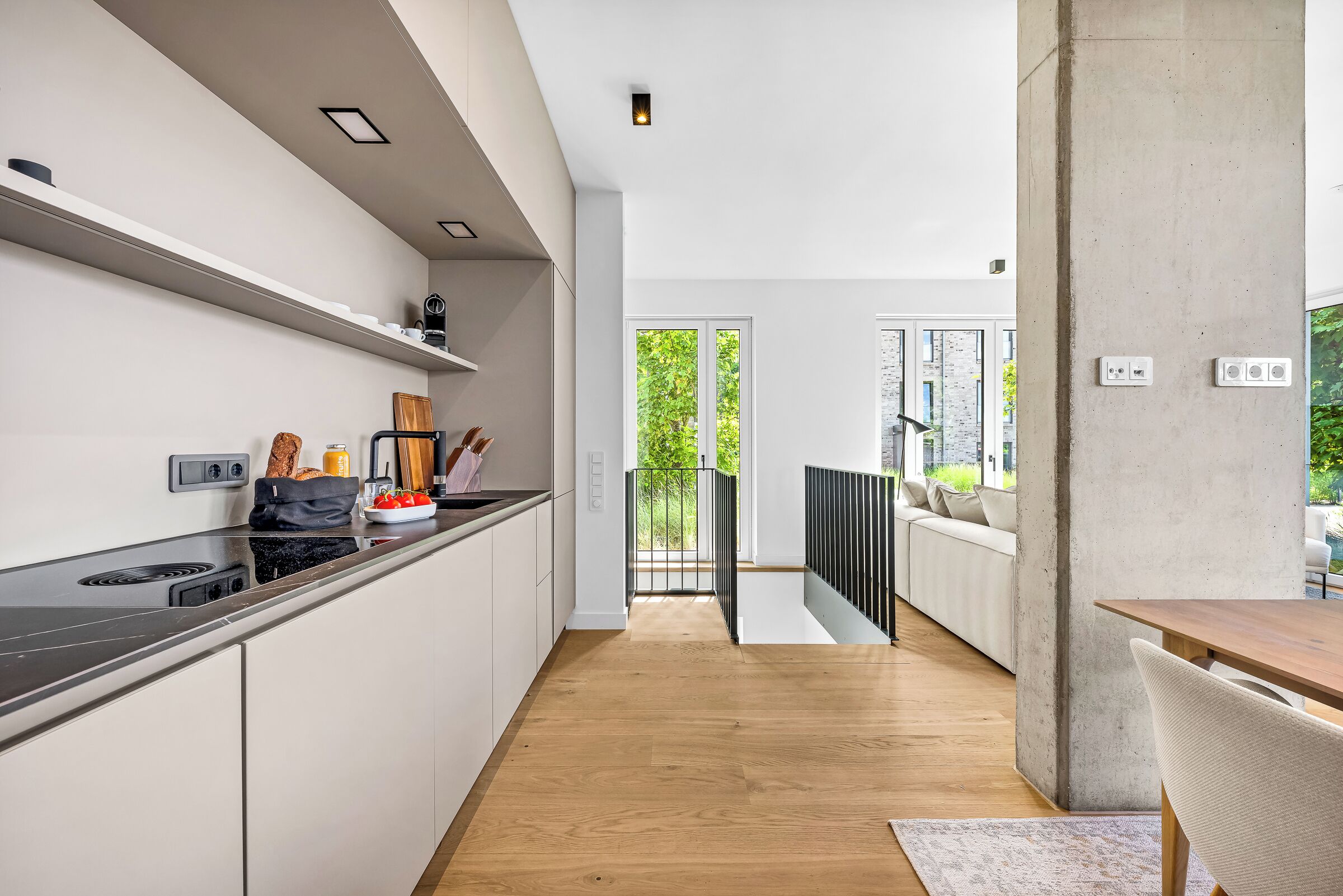 A modern kitchen with a wooden countertop, a built-in stove, and a view to an outdoor balcony.
