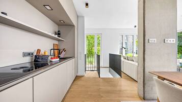 A modern kitchen with a wooden countertop, a built-in stove, and a view to an outdoor balcony.