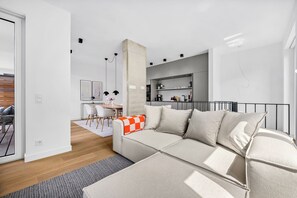 A modern living room with a sofa, a dining area, and a kitchen in the background. - Arriving between the sea, the light, and the open landscape (List auf Sylt)