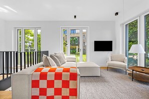 A modern living room with a sofa, a coffee table, and a TV mounted on the wall. - Arrival amid the sea, light, and open landscape (List auf Sylt)