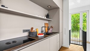 A modern kitchen with a black countertop, white cabinets, and a window with a view of greenery. - Arriving between the sea, the light, and the open landscape (List auf Sylt)