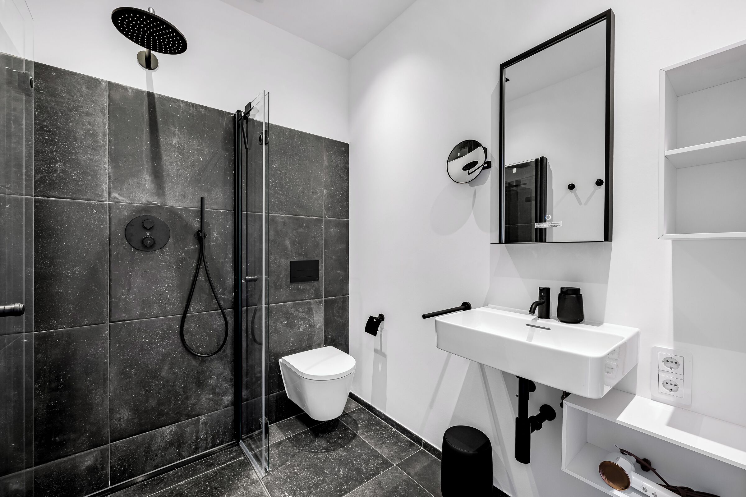 Een moderne badkamer met douche, toilet, wastafel en spiegel.