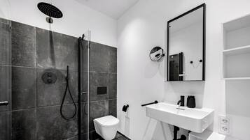 Een moderne badkamer met douche, toilet, wastafel en spiegel.