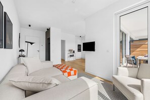 A modern living room with a sofa, a coffee table, and a TV mounted on the wall. - Arriving between the sea, the light, and the open landscape (List auf Sylt)
