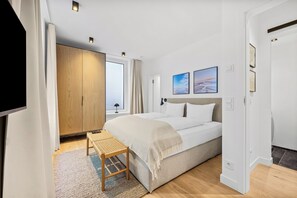 Une chambre moderne avec un grand lit, une petite table et une vue sur l’extérieur.