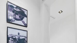 Ein Waschraum mit einer Waschmaschine, zwei gerahmten Bildern an der Wand und einem Lichtschalter.