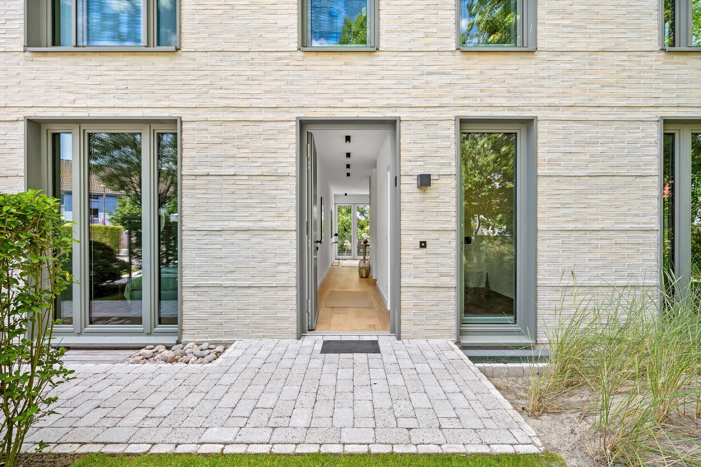 A modern building with a brick facade, large glass doors, and a central hallway leading to the entrance.