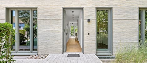En moderne bygning med en murstensfacade, store glasdøre og en central gang der fører til indgangen.