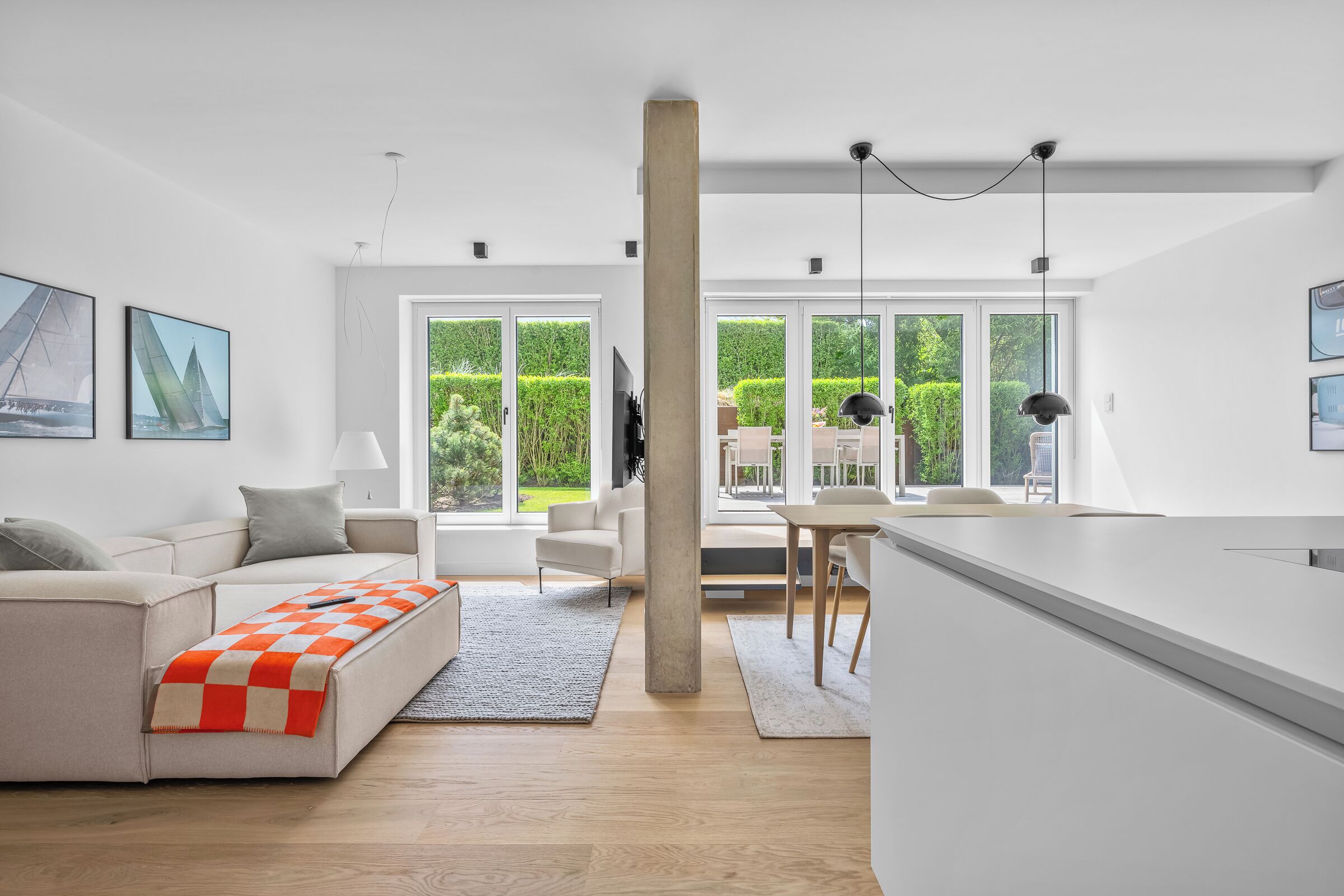 Uma sala de estar moderna com um sofá, uma mesa de centro e uma área de jantar com cadeiras e uma mesa.