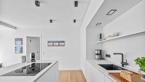A modern kitchen with a central island, built-in appliances, and a wooden floor. - Arriving between the sea, the light, and the open landscape (List auf Sylt)