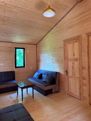A wooden interior with a sofa, a table, and a door.