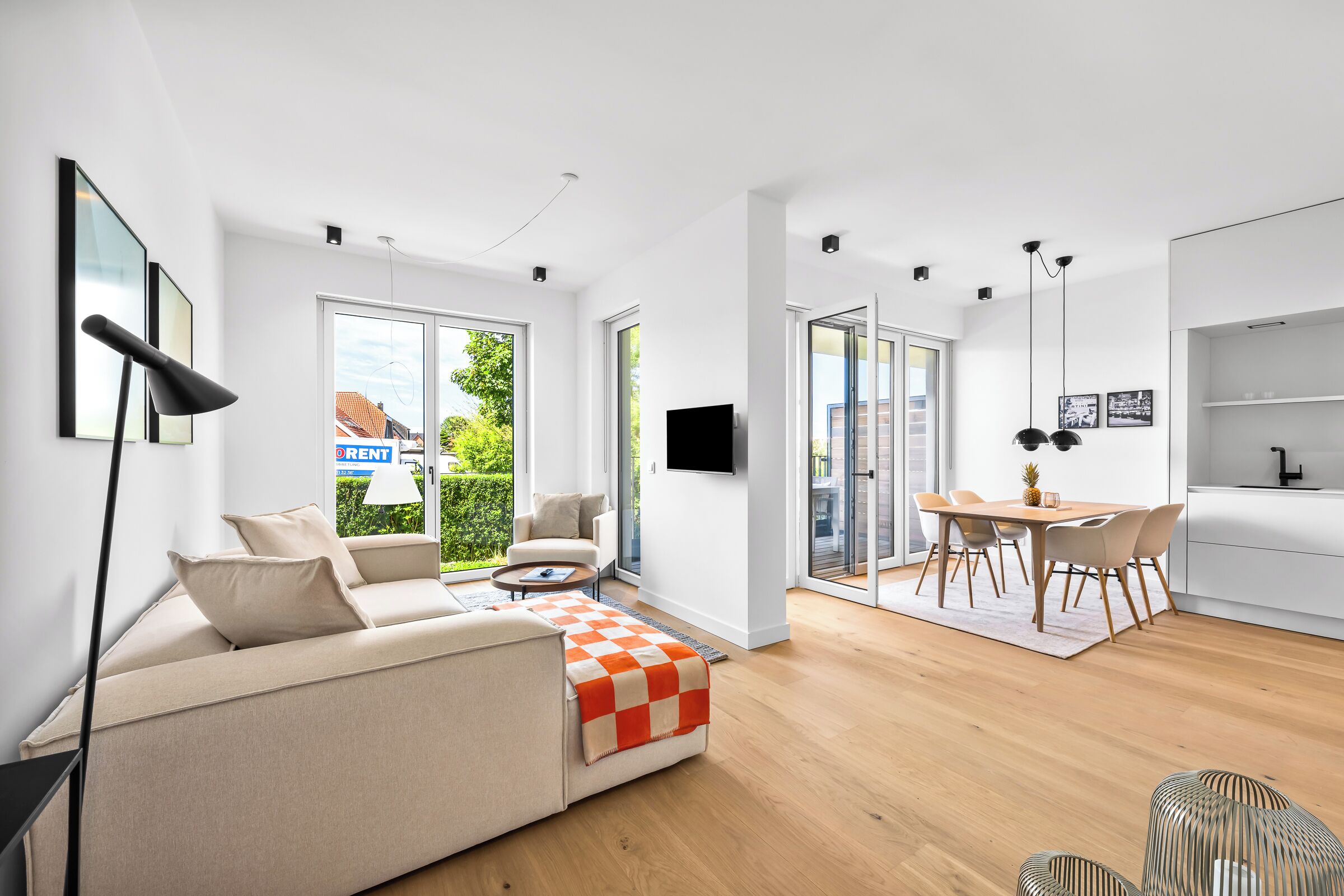 Een moderne woonkamer met een bank, een salontafel en een eethoek met stoelen en een tafel.