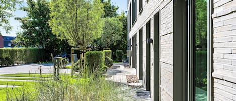 En moderne bygning med store vinduer, en belagt sti og velholdt beplantning.