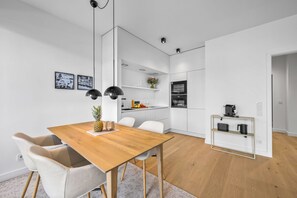 A modern kitchen with white cabinetry, a wooden dining table, and a coffee machine. - Arrival amid the sea, light, and open landscape (List auf Sylt)