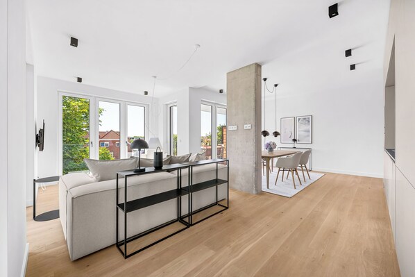 Ein modernes Wohnzimmer mit einer Couch, einem Couchtisch und einem Essbereich mit Stühlen und Tisch.