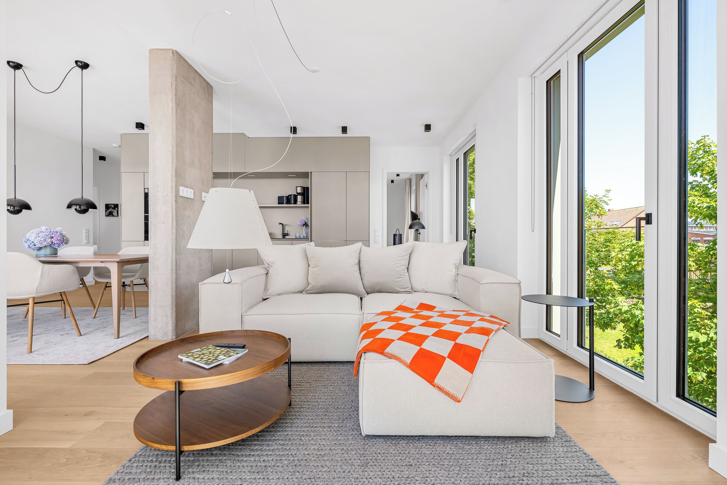 Ein modernes Wohnzimmer mit Sofa, Couchtisch und einem Essbereich mit Stühlen und Tisch.