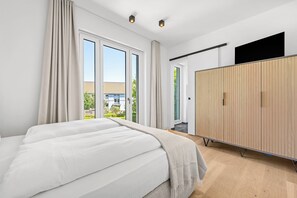 A modern bedroom with a large bed, a wardrobe, and a TV. - Arrival amid the sea, light, and open landscape (List auf Sylt)