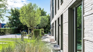 Un edificio moderno con ampie vetrate, un vialetto lastricato e una vegetazione curata.