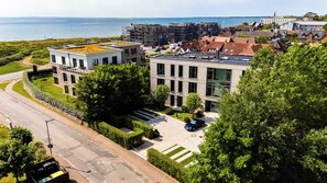Ein modernes Gebäude mit flachem Dach, umgeben von Grün und freiem Blick auf das Meer.