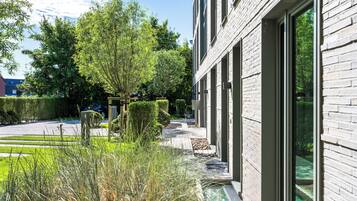 En moderne bygning med store vinduer, en belagt sti og velholdt beplantning.