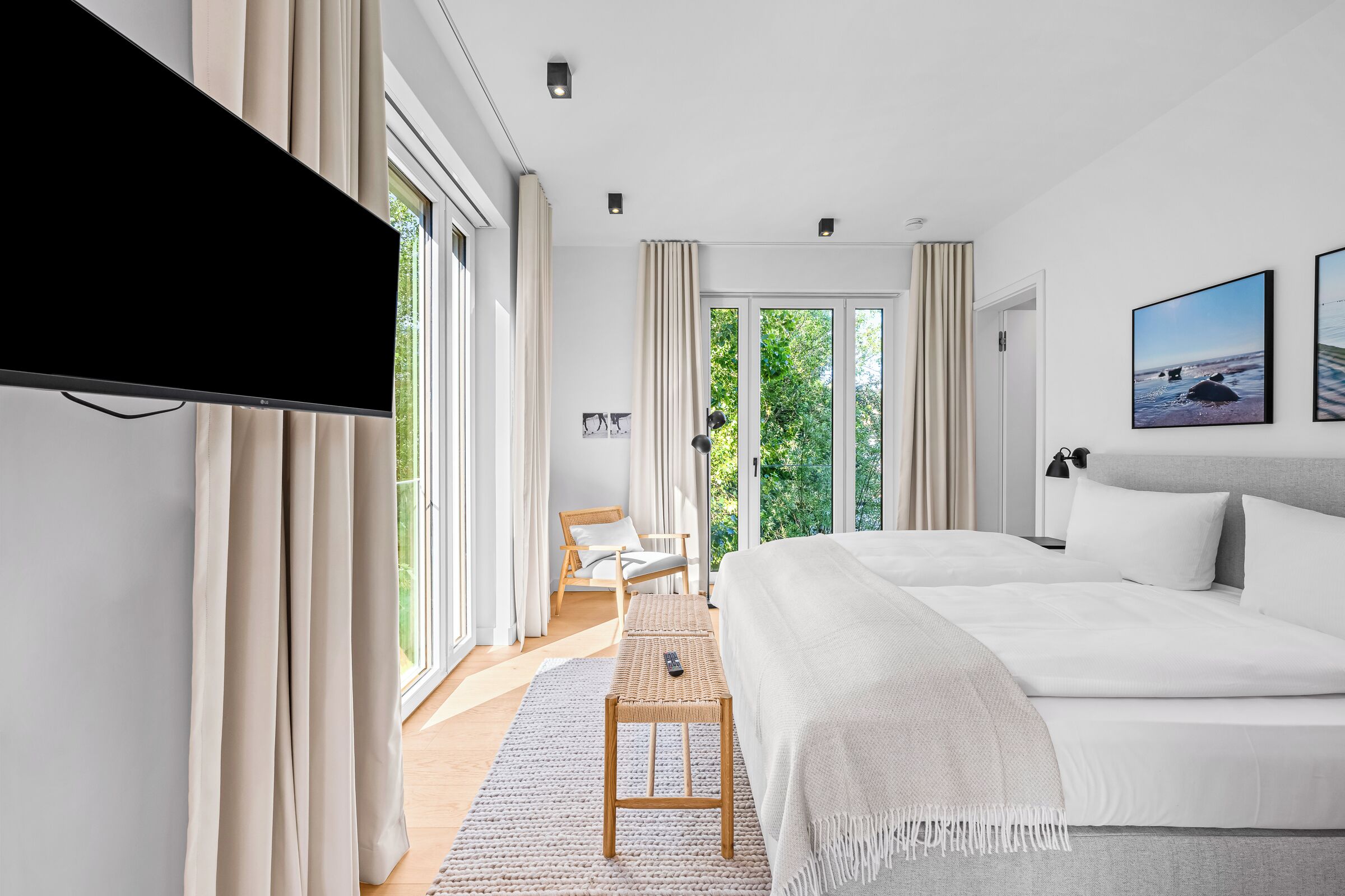 Une chambre moderne avec un grand lit, un téléviseur à écran plat, un bureau et une chaise.