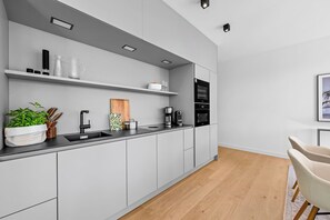 A modern kitchen with a black countertop, white cabinets, and a built-in oven. - Arriving between the sea, the light, and the open landscape (List auf Sylt)