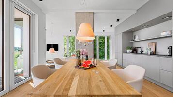 Un'area pranzo moderna con tavolo in legno, sedie bianche e un'ampia finestra.