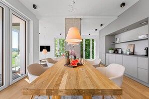 Ein stilvoller Essbereich mit einem Holztisch, weißen Stühlen und einem großen Fenster.