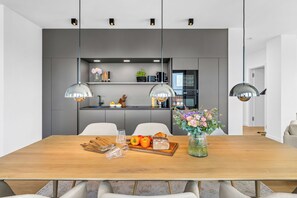 Un comedor moderno con una mesa de madera, sillas y un florero con flores.