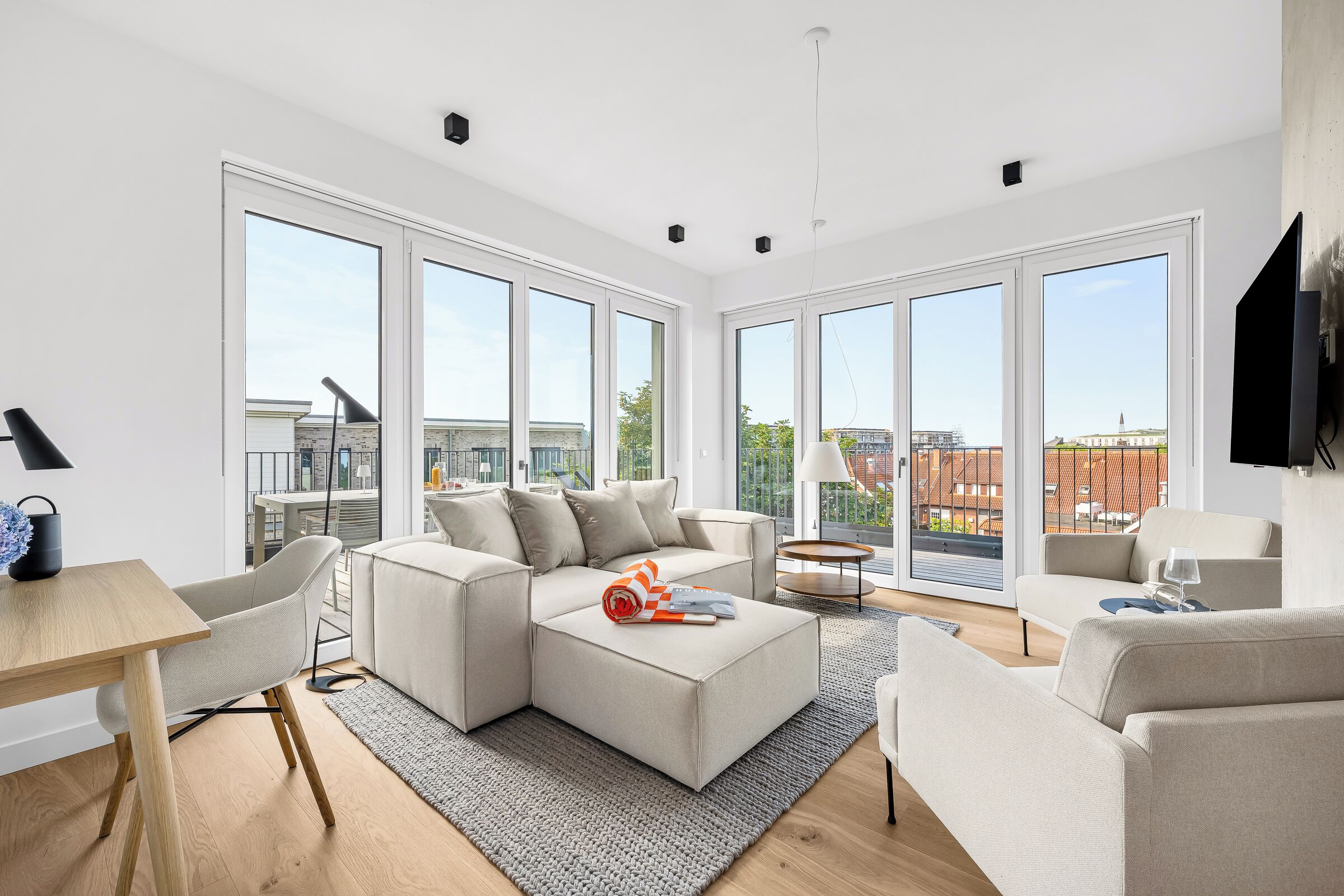 A modern living room with a sectional sofa, a small table, and a TV mounted on the wall.