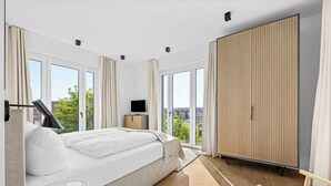 Une chambre moderne avec un grand lit, une télévision et une armoire.