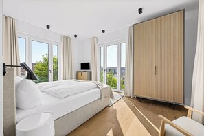 Ein modernes Schlafzimmer mit einem großen Bett, einem Fernseher und einem Kleiderschrank.
