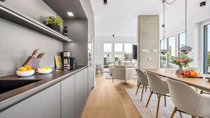 Une cuisine moderne équipée d’un four encastré, d’une machine à café et d’une plante posée sur le plan de travail.