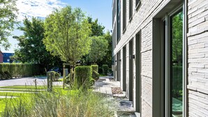 Un bâtiment moderne doté de grandes fenêtres, d’un chemin pavé et d’un espace vert bien entretenu.
