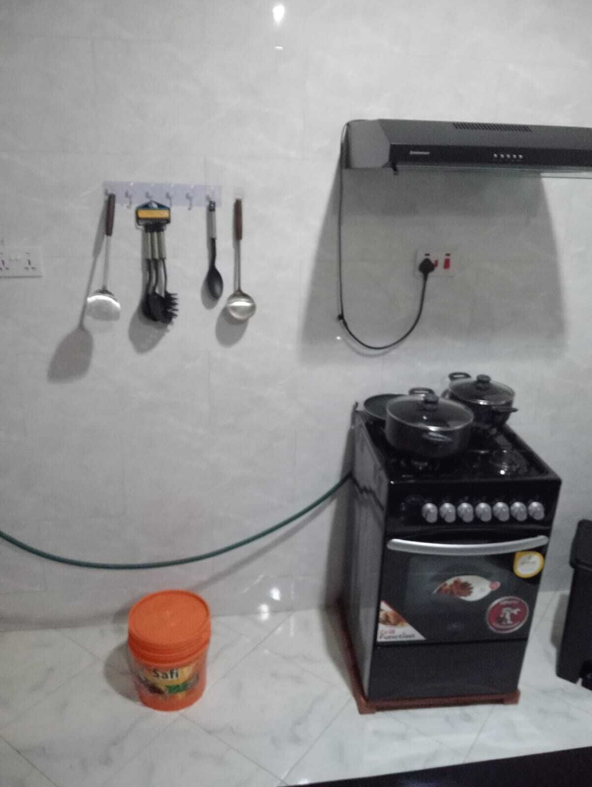Une cuisine équipée d’une cuisinière à gaz, d’une prise électrique murale et d’un porte-ustensiles suspendu.