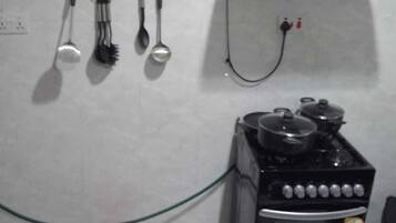 Une cuisine équipée d’une cuisinière à gaz, d’une prise électrique murale et d’un porte-ustensiles suspendu.
