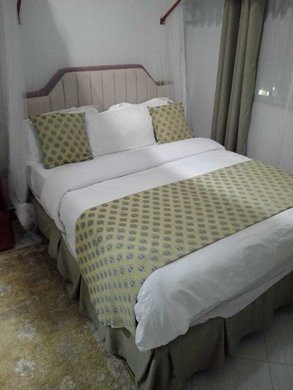 A bed with a patterned bedspread, a headboard, and pillows.