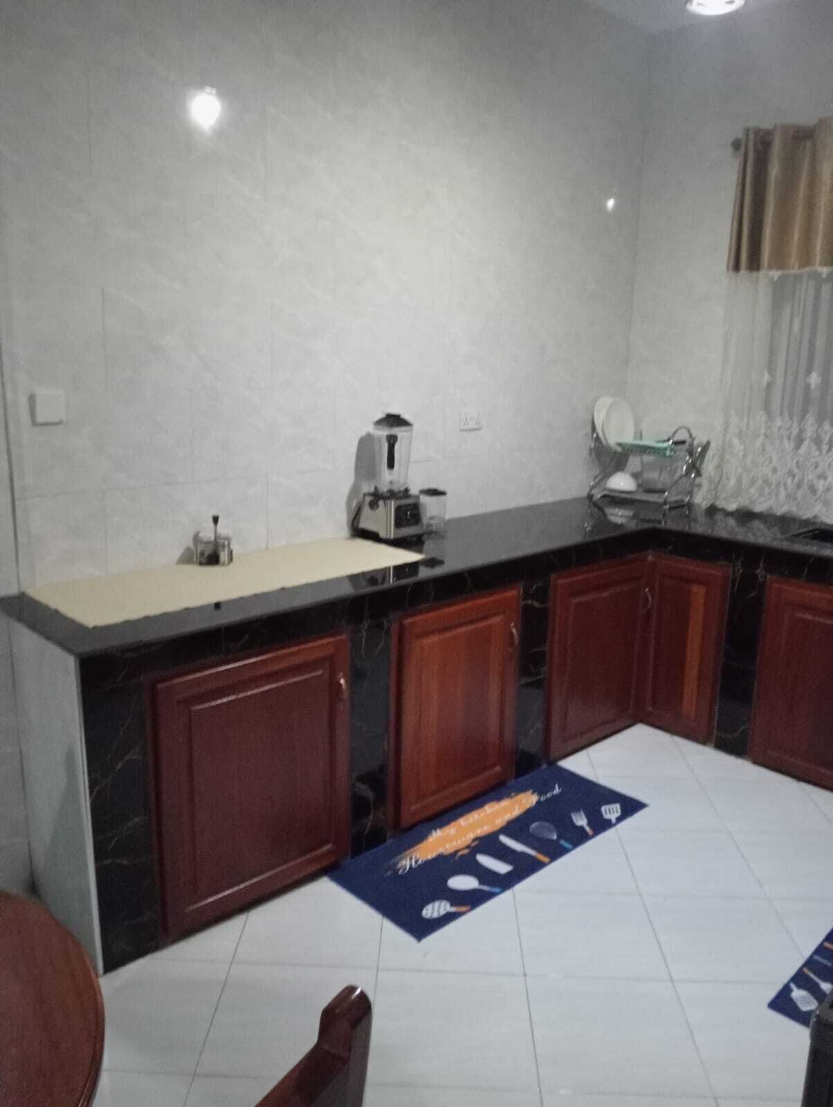 Cocina con encimera de mármol, armarios de madera, cafetera y un lavabo.