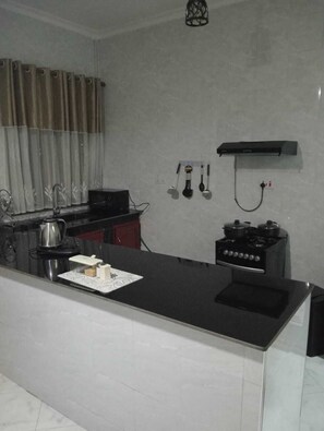 A modern kitchen with a black countertop, stainless steel appliances, and a wall-mounted stove.