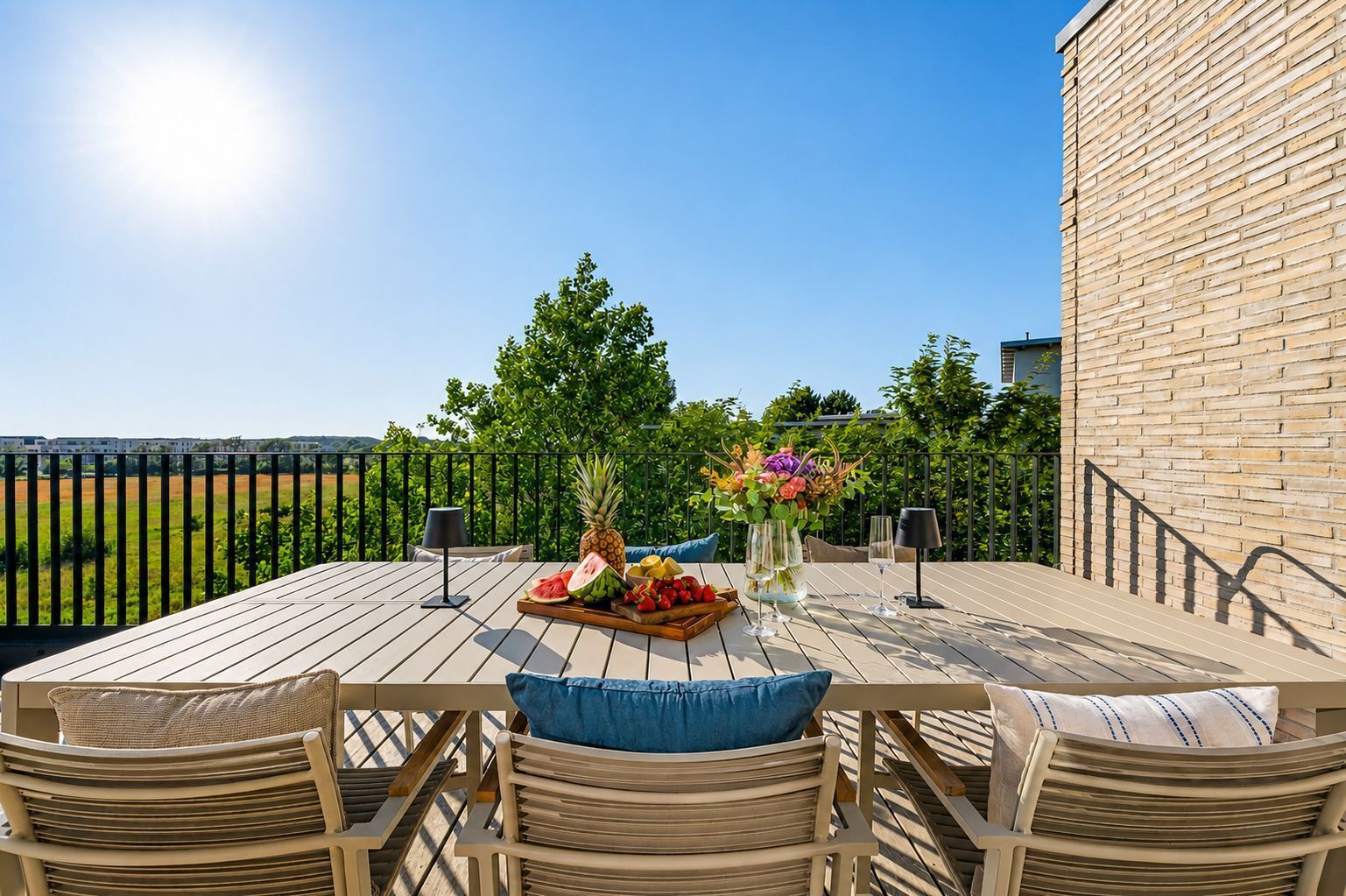 Eine Terrasse im Freien mit Holztisch, Stühlen und einer Obst- und Blumenkomposition.