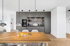 A modern kitchen with grey cabinets, a wooden dining table, and pendant lighting. - Arriving between the sea, the light, and the open landscape (List auf Sylt)