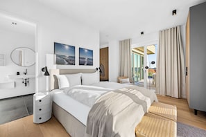 A modern bedroom with a large bed, a bedside table, a mirror, and artwork on the wall. - Arriving between the sea, the light, and the open landscape (List auf Sylt)