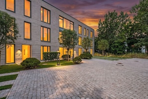 A modern building with a brick facade, large windows, and a paved courtyard. - Arriving between the sea, the light, and the open landscape (List auf Sylt)