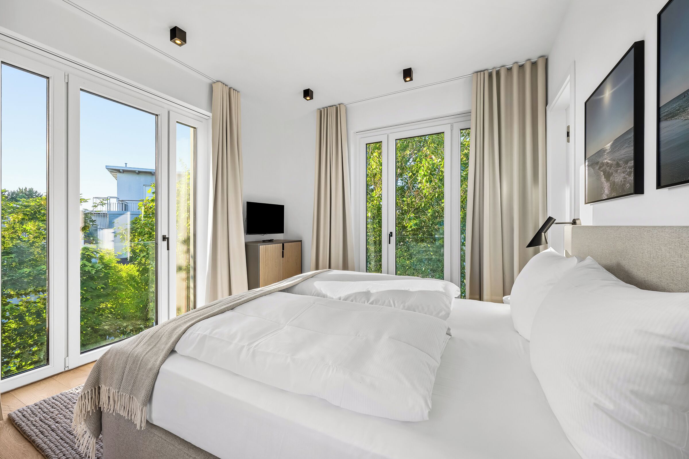 Een slaapkamer met een groot bed, een televisie en uitzicht op groen.