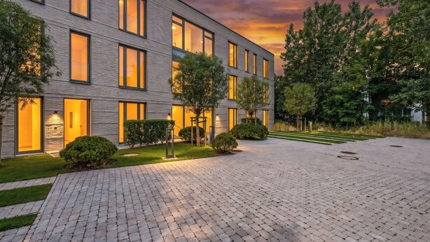 En moderne bygning med en murstensfacade, store vinduer og en anlagt gårdsplads.
