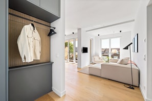 A modern living room with a sofa, a hanging coat, and a TV. - Arriving between the sea, the light, and the open landscape (List auf Sylt)