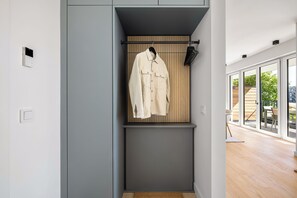 A modern interior with a coat rack, a wall-mounted light, and a view through large windows. - Arriving between the sea, the light, and the open landscape (List auf Sylt)