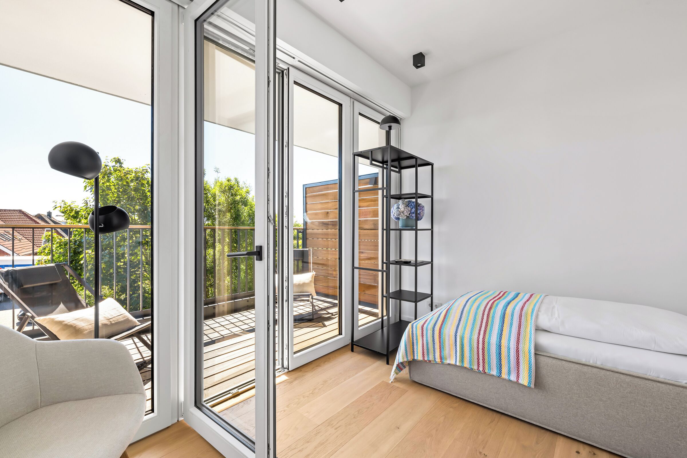 Una camera moderna con divano, una libreria e un balcone con mobili da esterno.